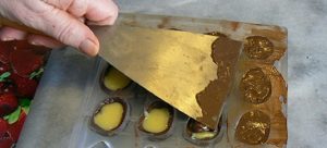 Schep gesmolten chocolade op de vulling en glad uitsmeren met een paletmes.